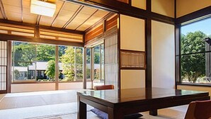 Una habitació tradicional japonesa amb fons de tatami, una taula de fusta baixa i portes corredisses.