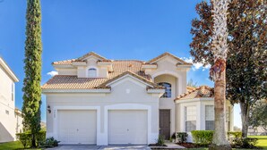 A two-story house with a tiled roof, two attached garages, and a well-maintained lawn. - Lovely 5 bedroom pool and spa home with fantastic cinema in Windsor Hills Resort (Kissimmee)