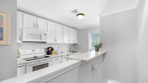 Een moderne keuken met witte kastjes, een ingebouwde magnetron en een fornuis.