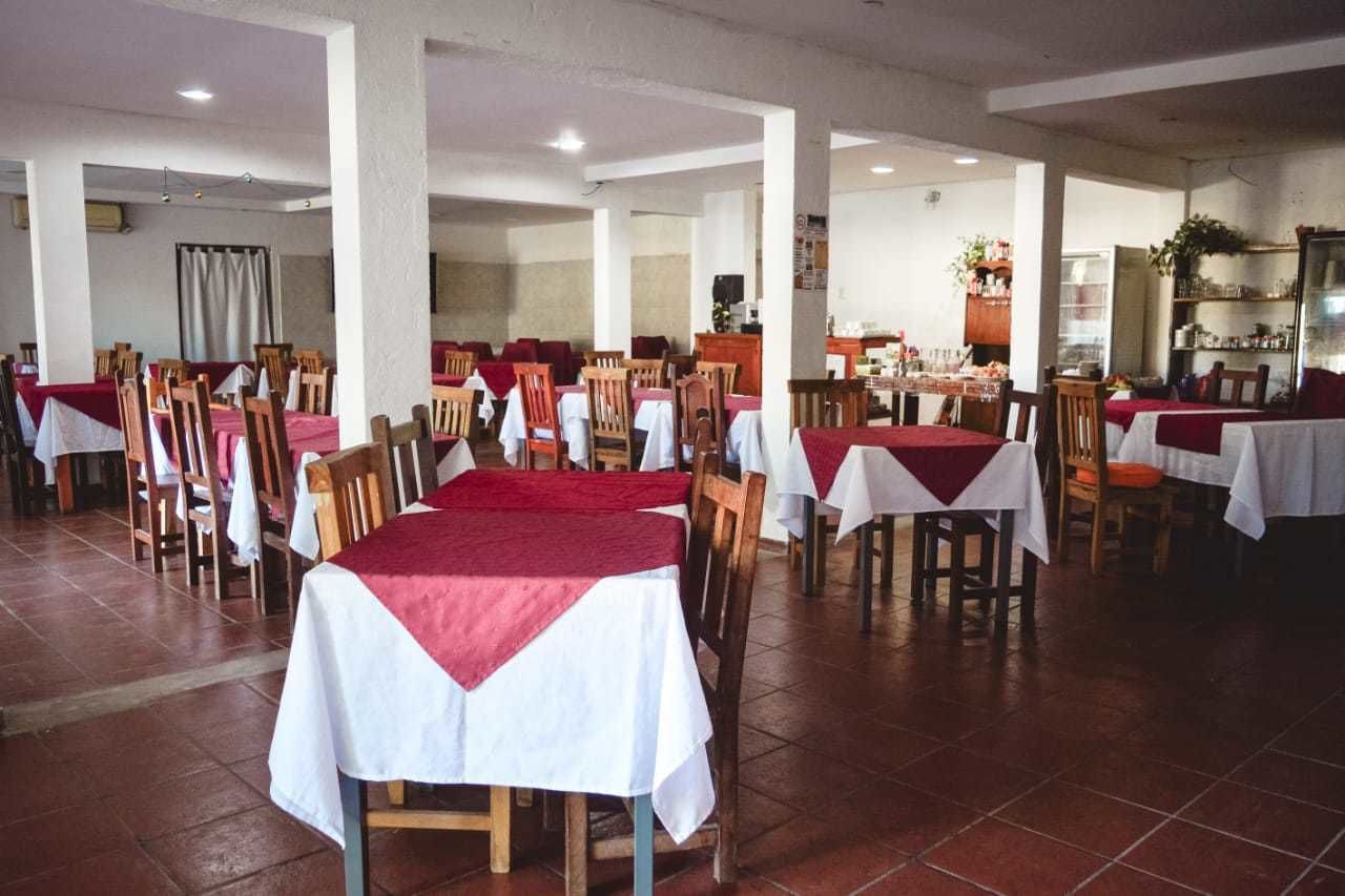 Un'ampia sala da pranzo con diversi tavoli e sedie, alcuni ricoperti da tovaglie bianche e rosse.