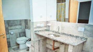 Un baño moderno con lavamanos de granito, inodoro y zona de ducha.