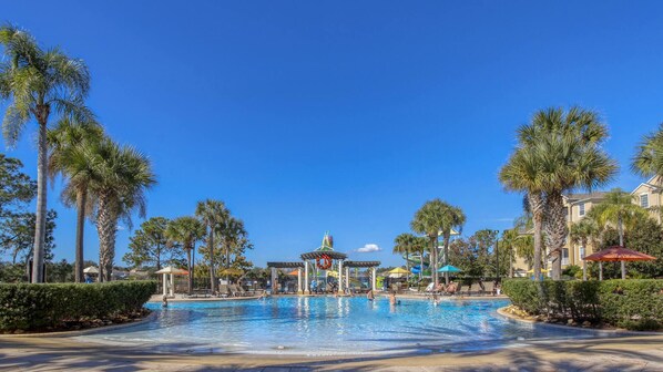 A swimming pool surrounded by palm trees and a water slide.