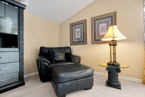 A room with a black leather chair, a glass table with a lamp, and two framed pictures on the wall. - Dazzling Disney Getaway - Closest to Disney  Villa with Private Pool & Game Room (Kissimmee)