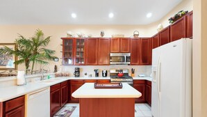Une cuisine avec des meubles en bois, un îlot central, un four à micro-ondes et un réfrigérateur.