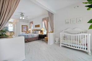 A bedroom with a bed, a crib, a nightstand, a lamp, and a ceiling fan. - Dazzling Disney Getaway - Closest to Disney  Villa with Private Pool & Game Room (Kissimmee)