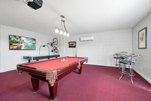 A pool table with balls, a bar area with stools, and a mounted television displaying a beach scene. - Dazzling Disney Getaway - Closest to Disney  Villa with Private Pool & Game Room (Kissimmee)