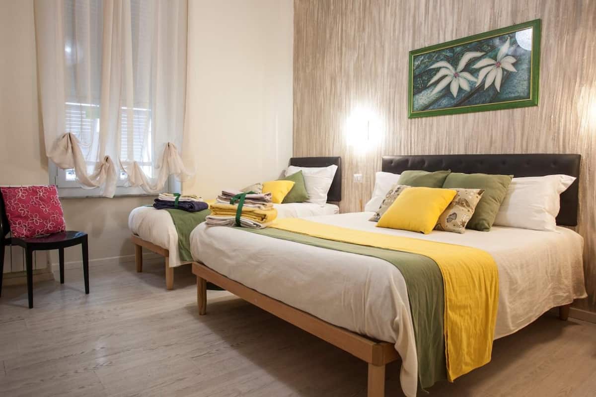 Une chambre bien rangée, avec un lit, des tables de chevet, une chaise et un tableau accroché au mur.