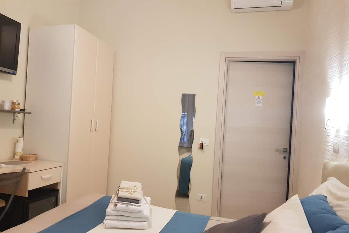 Une chambre d’hôtel avec un lit, un bureau, une armoire et une porte.
