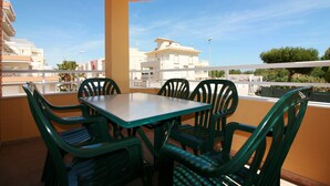 A balcony with a table and chairs, overlooking a residential area with buildings and trees. - OLIVA HOLIDAYS 2- BY THE SEA WITH SWIMMING POOL (Oliva)
