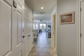 A hallway with white doors, a ceiling fan, and a dining area with chairs and a table.