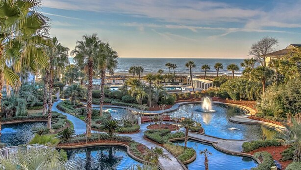 Ein Resort mit mehreren Pools, Palmen und Blick auf den Ozean.