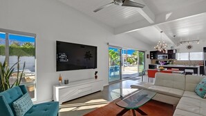 Un salon moderne avec un téléviseur, un canapé et une table basse en verre.