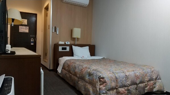 A hotel room with a bed, a desk with a lamp, a telephone, and a wall-mounted air conditioner. - Leo Plaza Hotel Sasebo (Sasebo)