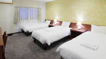 A hotel room with three beds, a carpeted floor, and a floral wallpaper.