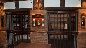 Un área de bar con vigas de madera y paredes de ladrillo, que incluye una estantería para vinos y un espejo.