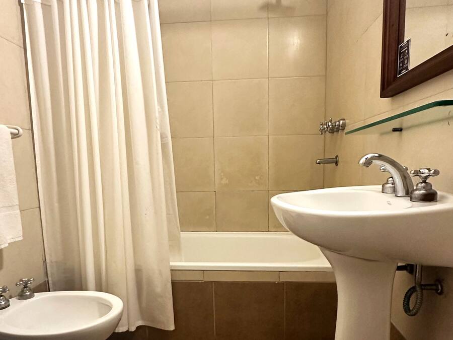 A bathroom with a bathtub, a sink, and two toilets.