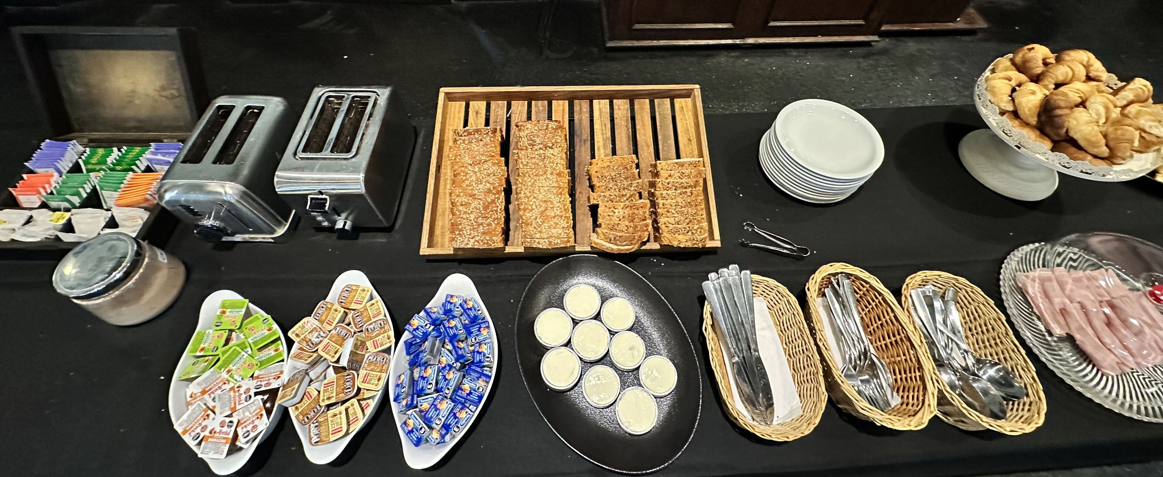 Una mesa de buffet con diversos alimentos, como pan, pasteles y salsas.