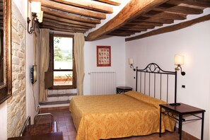 Un dormitorio con cama, mesita de noche, lámpara y ventana con cortinas.