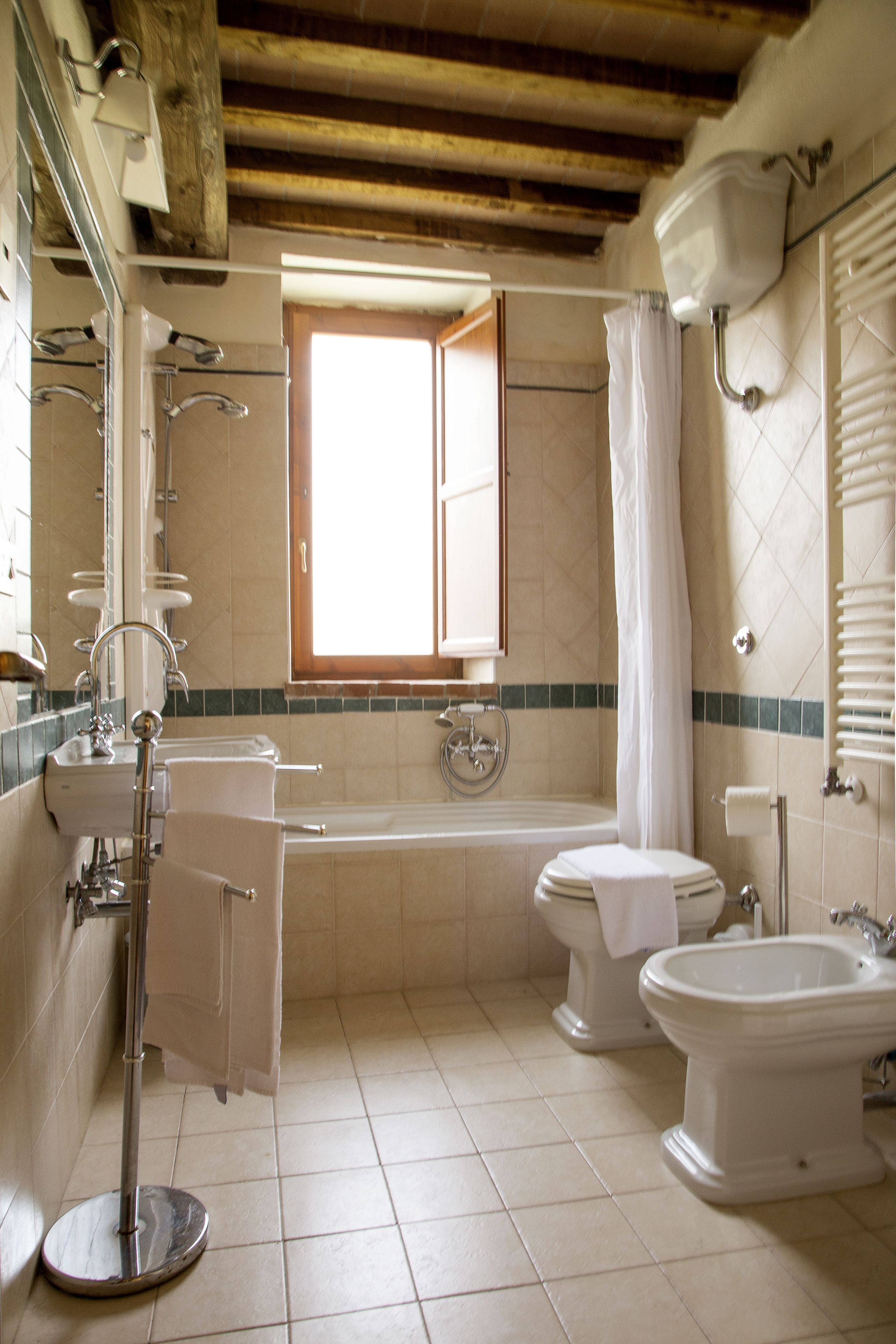 A bathroom with a bathtub, toilet, bidet, and a large mirror.