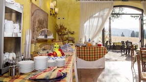 A breakfast buffet setup with plates, bowls, and a fruit basket. - Country House Santa Felicita la Paterna (Città di Castello)