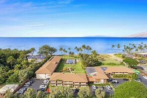 Un hotel frente al mar con varias construcciones, estacionamiento y paneles solares.