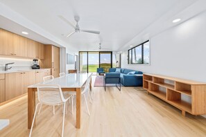 Una cocina moderna con armarios de madera, una mesa de comedor con sillas, un sofá azul y una estantería de madera.