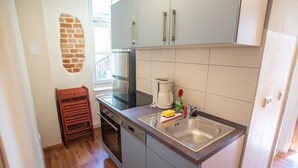 Une cuisine compacte avec des meubles gris, un évier en acier inoxydable, une machine à café et un égouttoir à vaisselle.