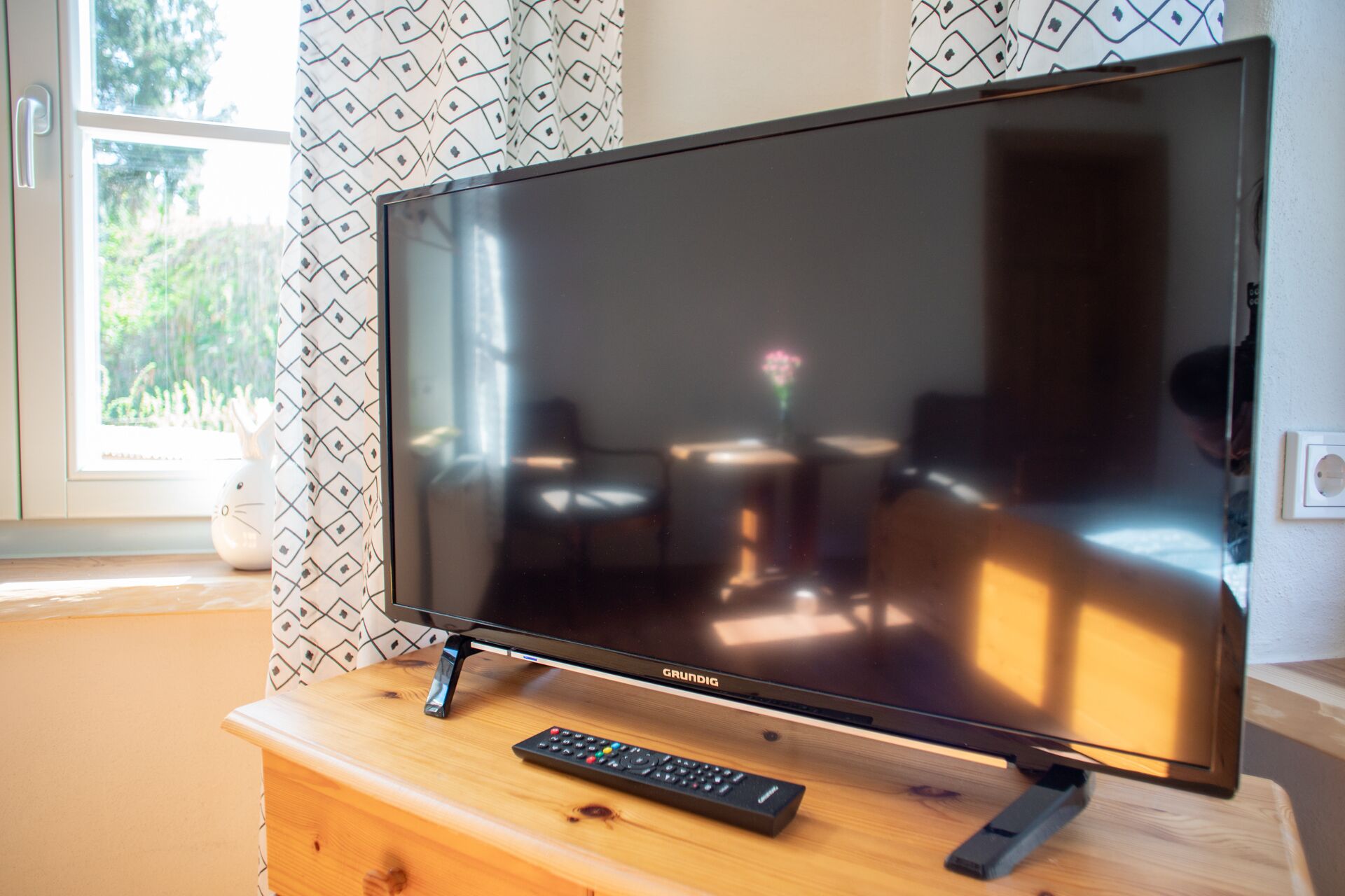 Ein Fernseher auf einem Holzboden mit einer Fernbedienung daneben.