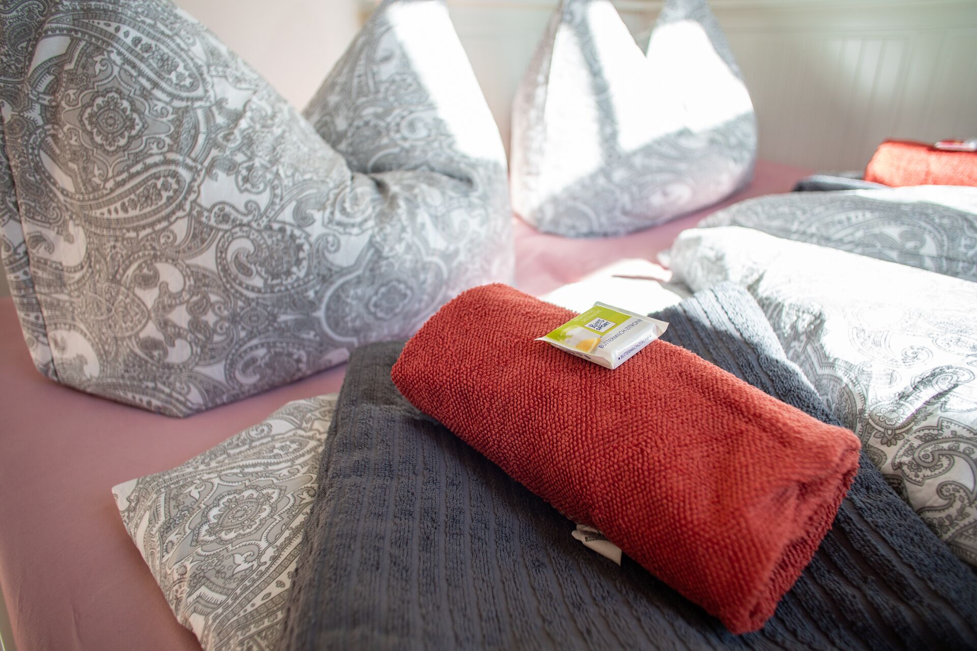 Una cama con almohadas estampadas y una colcha roja.