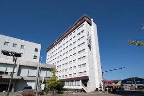 A multi-story hotel with a modern design, featuring a prominent entrance with a staircase and a covered area.