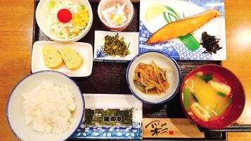 A variety of Japanese dishes including sushi, tempura, and a bowl of soup, arranged on a wooden table.