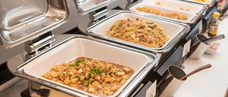 A buffet with multiple food stations, each with a covered serving tray.