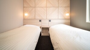 A hotel room with two single beds, a wooden headboard, and wall-mounted lights.
