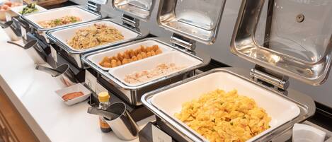 A buffet with multiple food stations, including scrambled eggs, tater tots, and other dishes.