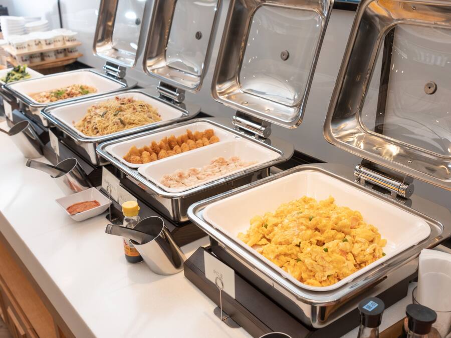 A buffet with multiple food stations, including scrambled eggs, tater tots, and other dishes.