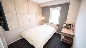 Una habitación de hotel moderna con cama, escritorio, silla y ventana.