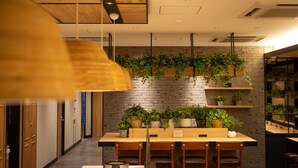 A modern interior with a wooden ceiling, hanging plants, a brick wall, and a wooden table with chairs.