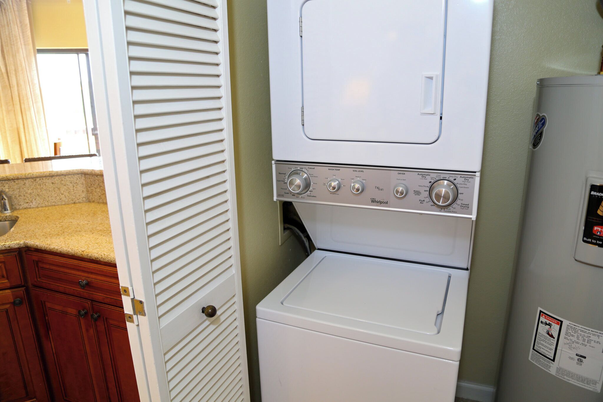 Un espace buanderie équipé d’un lave-linge et d’un sèche-linge à chargement frontal, de meubles en bois et d’un plan de travail.