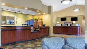 A reception area with a curved wooden desk, a flat-screen TV, and a patterned carpet. - Laurel Crest Vacation Resort in the Smoky Mountains. (Pigeon Forge)