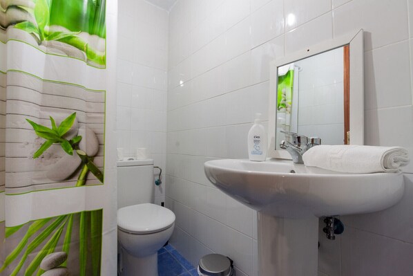 A bathroom with a white sink, toilet, and shower area.