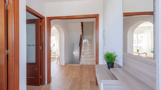 Ein Flur mit Holztüren, einer Treppe und einem Blumentopf.