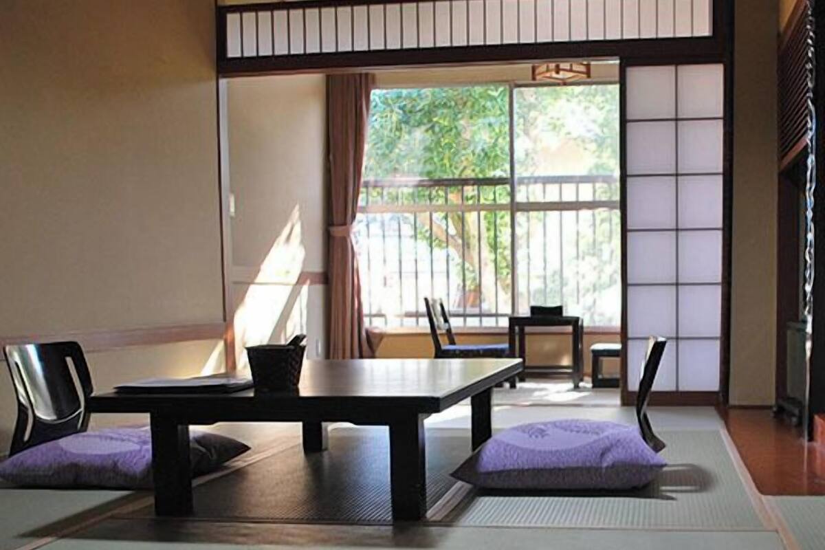 Une pièce de style japonais traditionnel, avec un sol recouvert de tatamis, une table basse et des coussins.