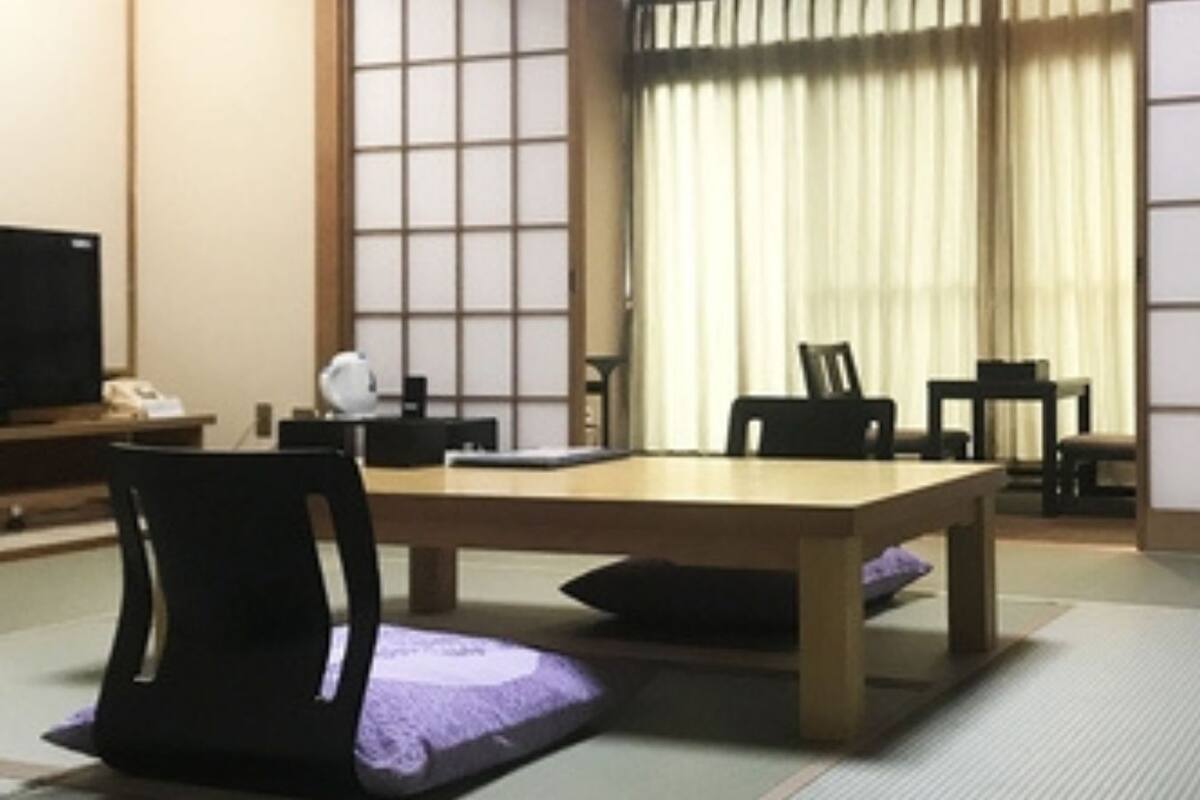 Une pièce de style japonais traditionnel, avec un sol recouvert de tatamis, une table basse et des chaises noires.