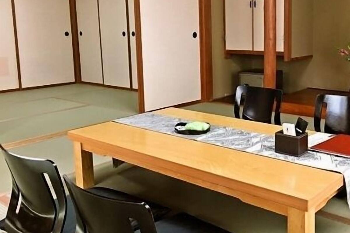 Une pièce de style japonais traditionnel, avec un sol recouvert de tatamis, une basse table en bois et des chaises noires.