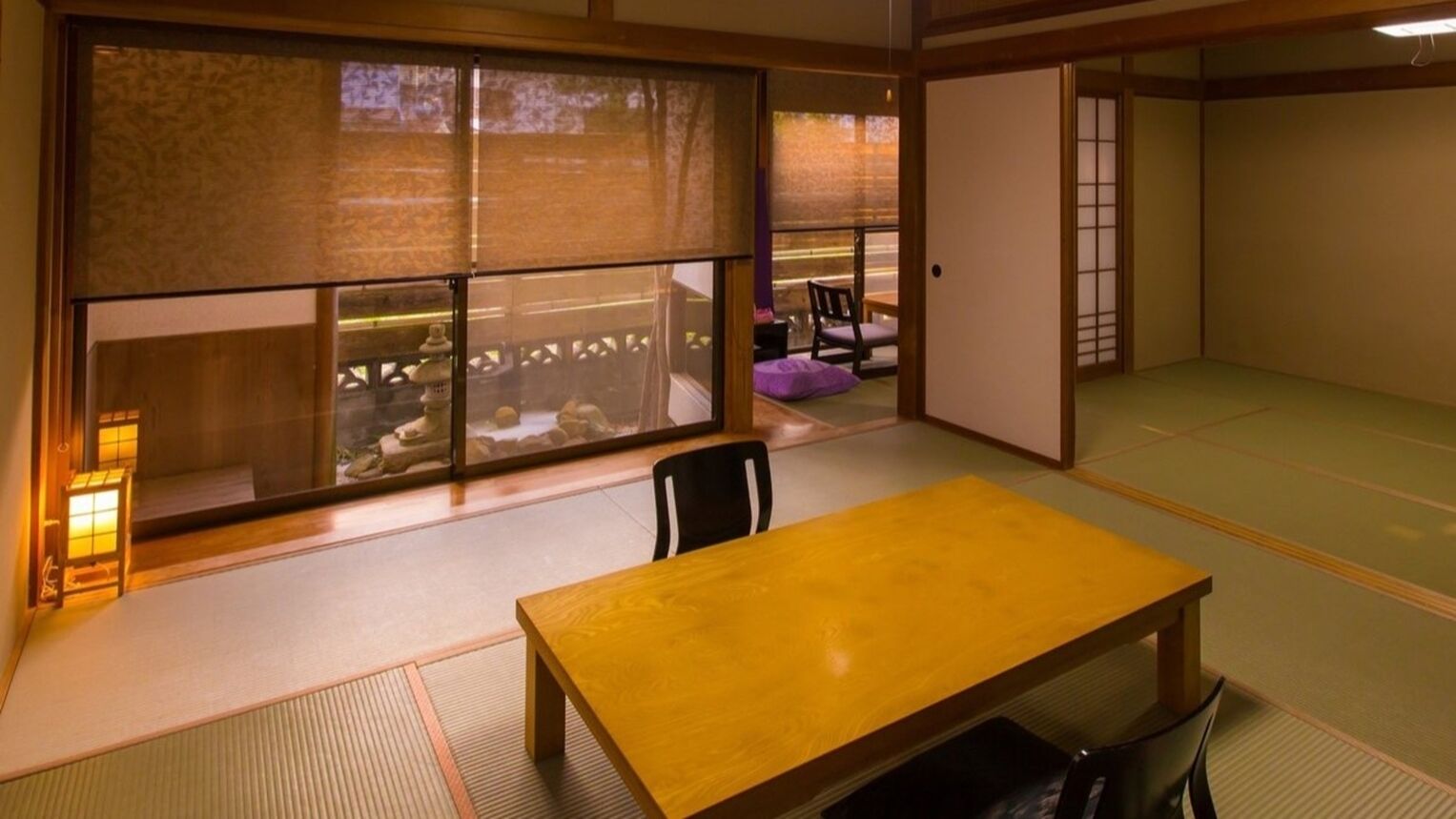A traditional Japanese room with tatami flooring, a wooden table, and sliding doors.