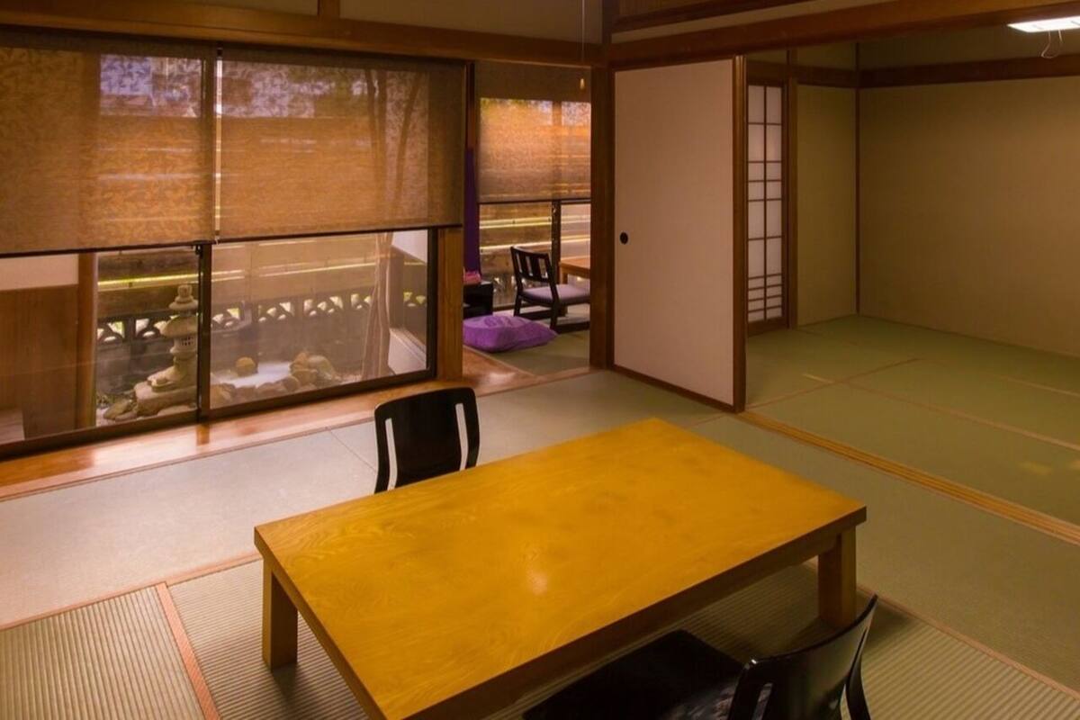 Une pièce de style japonais traditionnel, avec un sol recouvert de tatamis, une table en bois et des portes coulissantes.