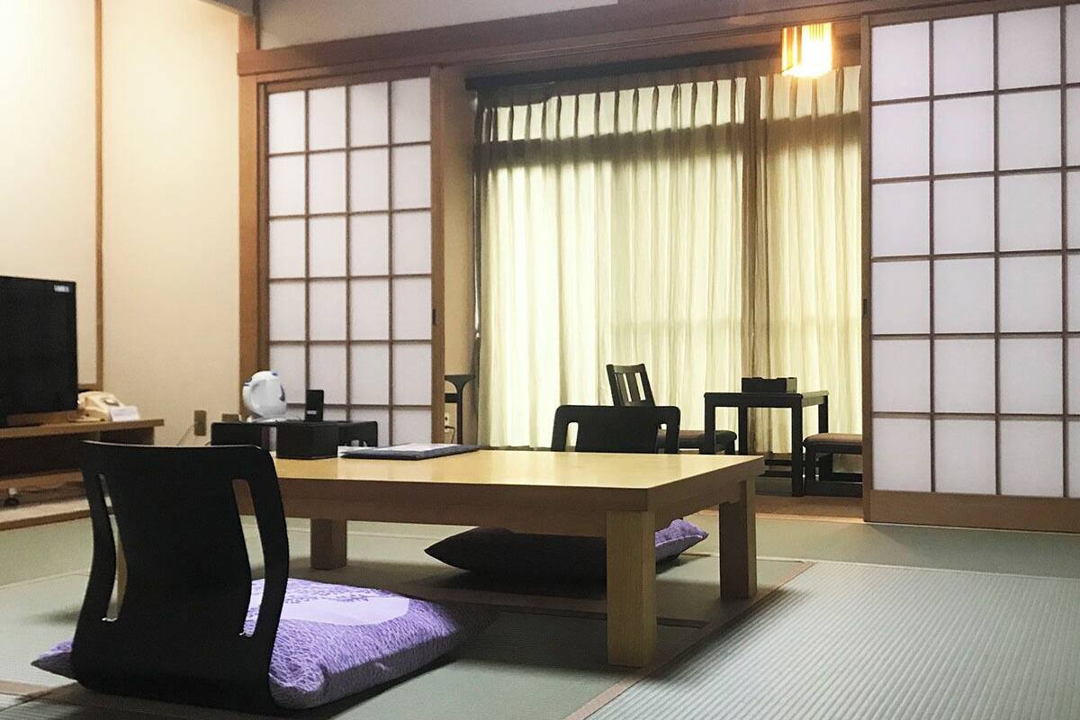 Une pièce de style japonais traditionnel, avec un sol recouvert de tatamis, une table basse et des chaises.
