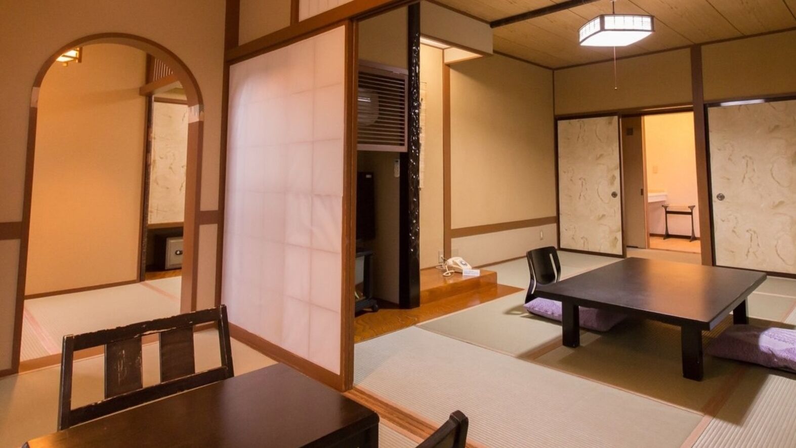A traditional Japanese room with tatami flooring, a low table, a chair, and sliding doors.