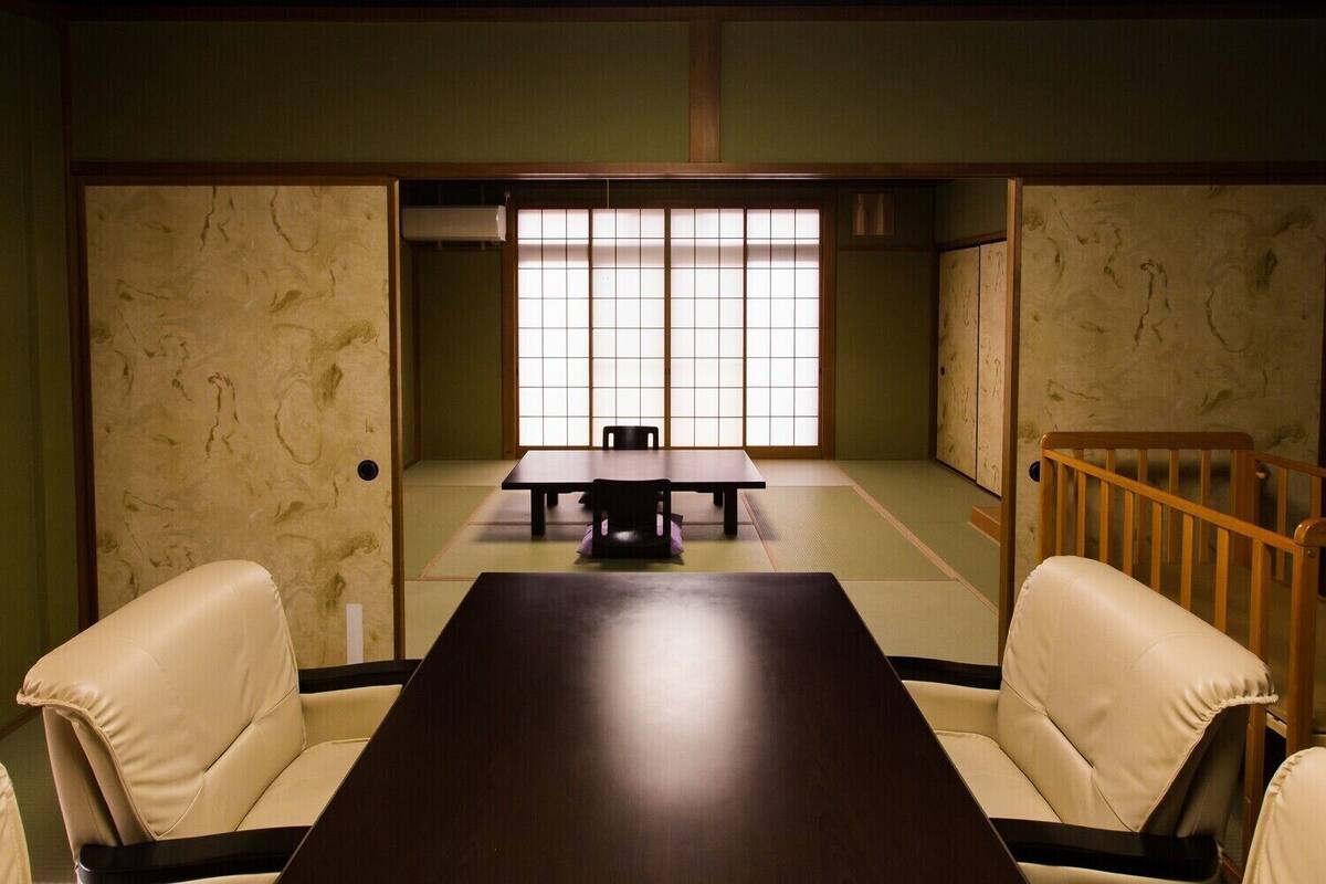 Une pièce de style japonais traditionnel, avec un sol recouvert de tatamis, une table basse et deux fauteuils rembourrés.