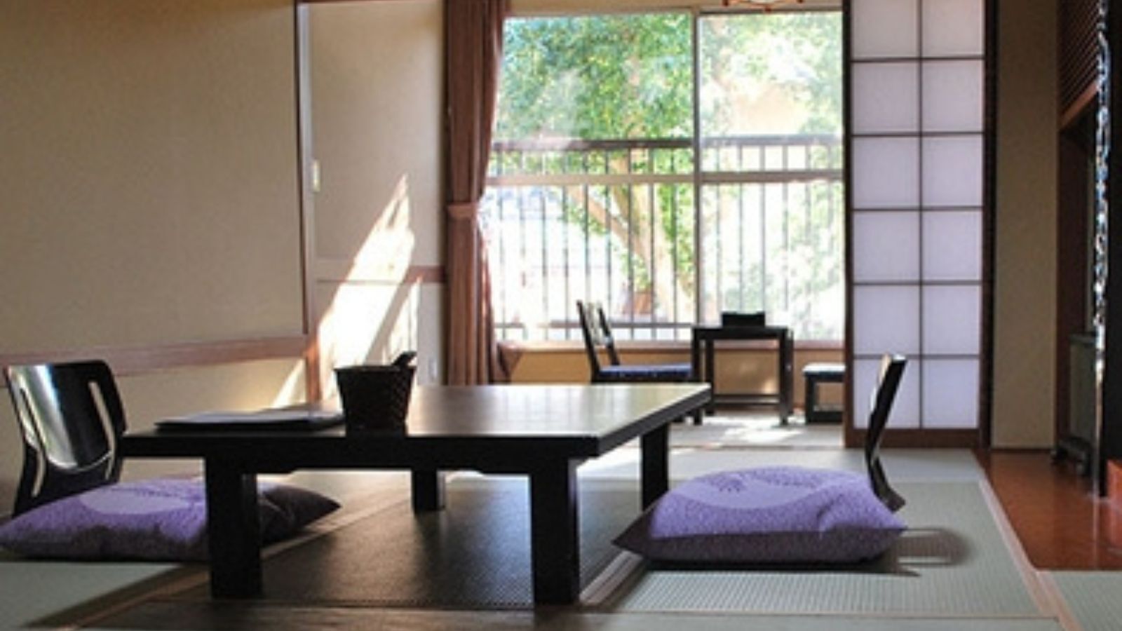 A traditional Japanese room with tatami flooring, a low table, and chairs.